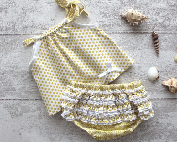 Ensemble de bain jaune à pois avec volants, accompagné de coquillages décoratifs.