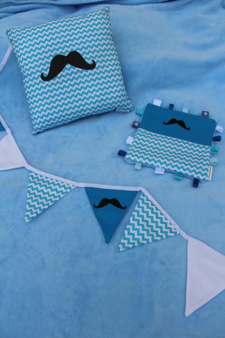 Coussins et fanions décoratifs à motifs de moustaches sur fond bleu.
