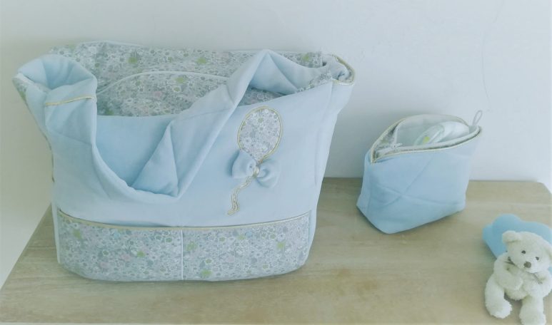 Sac en tissu bleu clair avec un motif floral et une petite trousse assortie sur une table.